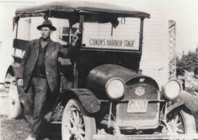 "Oscar W. Stuart standing by his Cundy's Harbor Stage is at his home in Cundy's Harbor. The date is 1920. Oscar ran a regular daily schedule from Cundy's Harbor to Brunswick, stopping at the train station, postoffice and hotelsd. He ran his route approximately 12 years." From letter from Virginia G Stuart to Mrs. F. W. Browne, (no date)